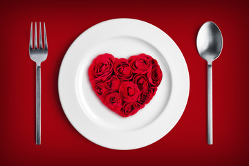 Red heart shape made of flowers on white plate for valentine's day.