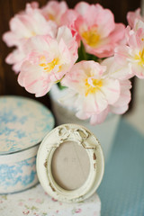 Vintage frame with bow decoration. Gift boxes with flower ornament. Bouquet of tulips with pink and white petals in white metal vase.