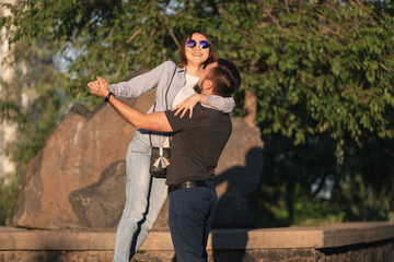 A loving couple of young people of Asian appearance walk around the city. The guy holds his lover's hand. The girl laughs and hugs her lover.