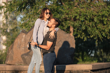 A loving couple of young people of Asian appearance walk around the city. The guy holds his lover's hand. A girl with a smile on her face hugs her lover.
