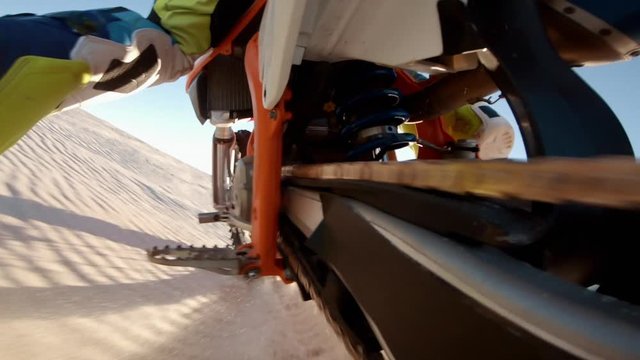 Shot from action camera mounted on the rear swingarm of a dirt motorbiker riding on sand dunes. Dirt biker off roading on sand dunes in desert..