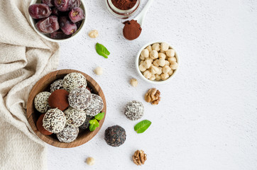 Energy balls. Truffles of dates, walnuts, hazelnuts and cocoa in a wooden bowl on a light background. Healthy dessert, sugar-free, gluten-free. Horizontal orientation. Top view, copy space.
