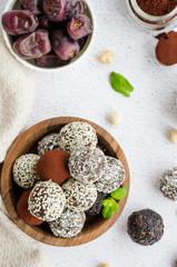 Energy balls. Truffles of dates, walnuts, hazelnuts and cocoa in a wooden bowl on a light background. Healthy dessert, sugar-free, gluten-free. Vertical orientation. close up.