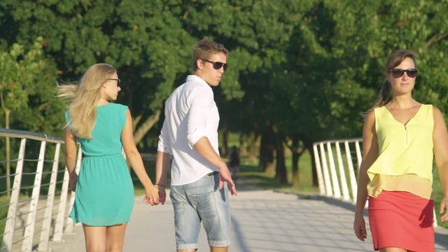 SLOW MOTION, CLOSE UP: Jealous blonde girl strikes her boyfriend for looking at another woman walking past them during their stroll in the park. Funny shot of irritated girl slapping her boyfriend.