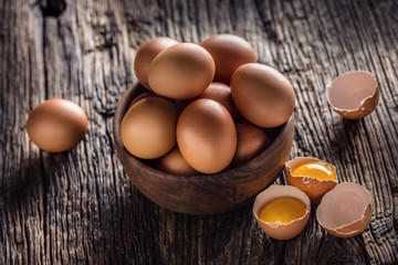 Chicken eggs in wooden bowl on rustic oak table