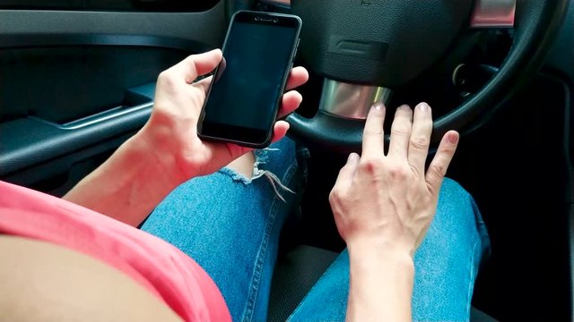 Woman sits in the car and texting a message, soft focus background