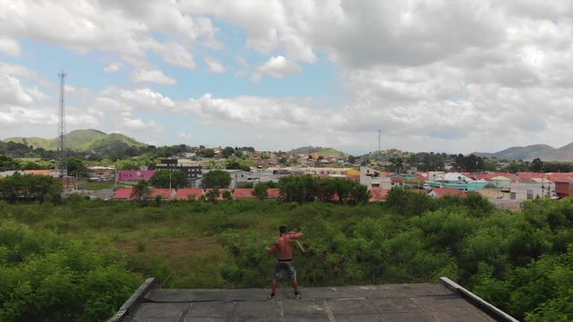 drone video of a man doing martial arts tricks with a pole on a rooftop