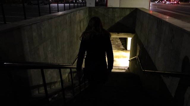 Girl walking down to the underground passage at night