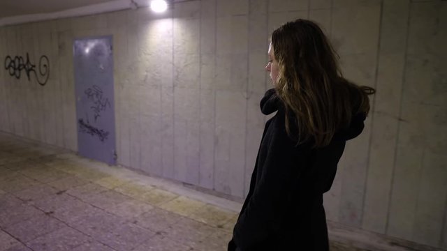 Girl walking in the underground passage at night time
