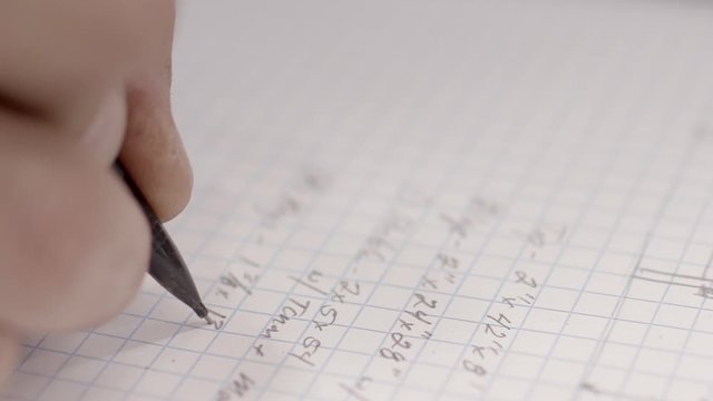 A math equation with numbers and fractions is written out in a notebook, close up