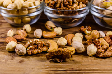 Various nuts (almond, cashew, hazelnut, pistachio, walnut) in glass bowls on a wooden table. Vegetarian meal. Healthy eating concept