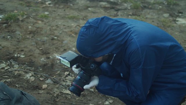 Criminal investigator taking photos of crime scene, high angle closeup