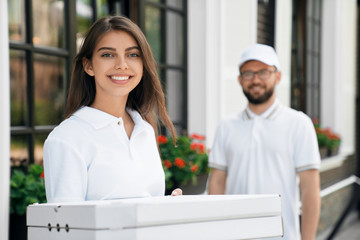 Smiling woman holding boxes of pizza.