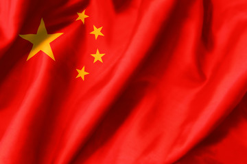 China national flag waving in the wind. Closeup of red silk standard of Republic of China with yellow stars. The People's Republic of China colors background.