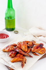 Grilled chicken wings with beer and red sauce on a wooden background. Snack to beer. Barbecue. Recipes.