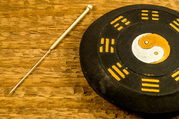 acupuncture needle beside Chinese Taoism symbol