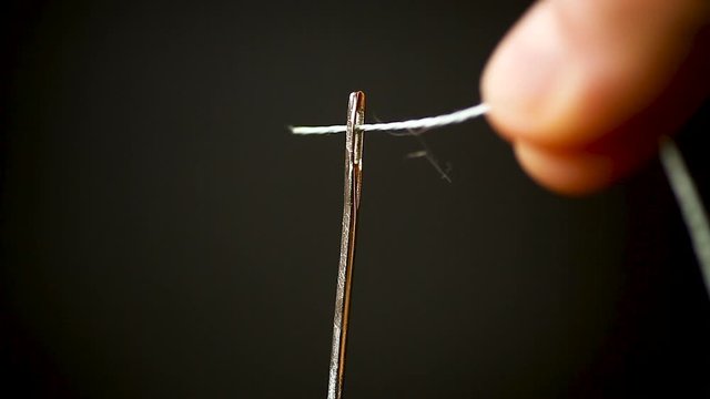 thread stuck in a needle close-up on a black