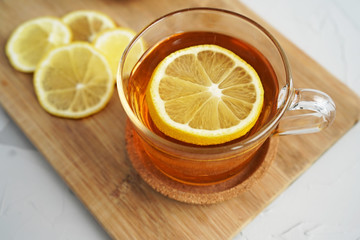 Warm tea with lemon on a wooden board. A warming drink for colds. The healing properties of lemon