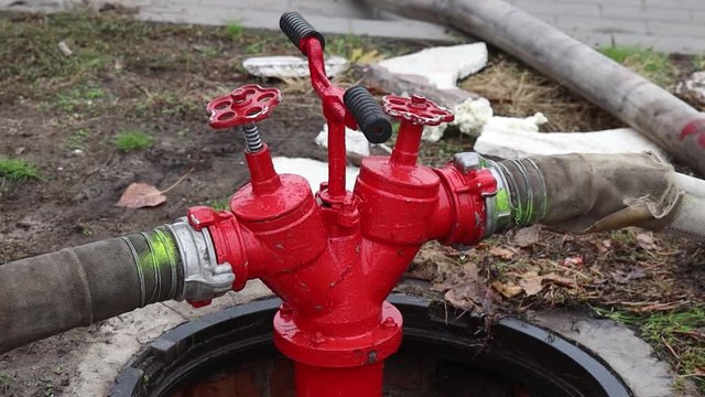 Fire hydrant on the side of the street lit by street lamps. Red fire hydrant in rainy weather. footage