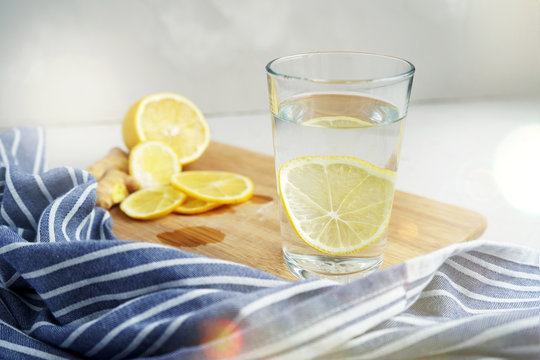 Refreshing drink with lemon on a gray background. Warm water with a slice of lemon next to a blue napkin