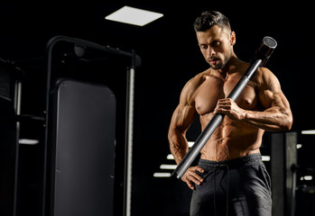 Fototapeta na wymiar Muscular bodybuilder holding sledgehammer on shoulder.