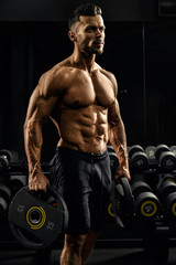Fototapeta na wymiar Tensed male bodybuilder holding weights.