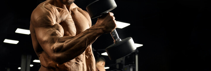 Male bodybuilder training biceps with dumbbell.