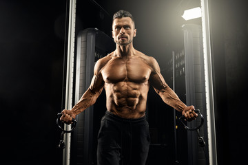 Fototapeta na wymiar Muscular bodybuilder doing crossover chest exercise.