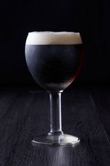 Black beer texture standing at black background.