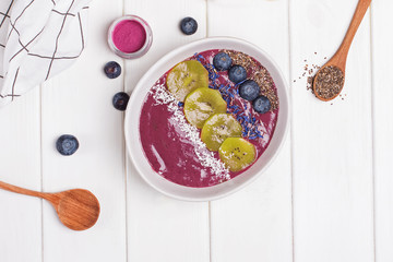 Acai berry smoothie bowl topped with seeds, flowers and blackberries