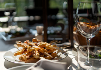 Baked bacon with dough on wooden skewers. Backlight, an empty glass of wine.
