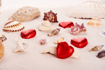 Chocolate red praline hearts on the beach sand on St. Valentine's Day