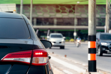 Luxury of black car open brake light on the road. Park to wait for traffic signals. And blurry images of cars coming from the opposite side.