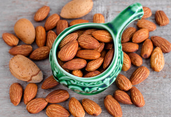 Almonds in the green bowl. Nuts close up. Old wooden backgdound.