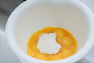 Egg yolks with proteins in a white plate are waiting for cooking
