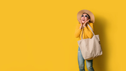 Portrait of an excited beautiful girl wearing dress and sunglasses holding shopping bags. Cheerful young woman with handbag on yellow background. Shopaholic shopping Fashion.