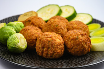 Cooking of healthy vegetarian food, tasty check pea falafels and frehs green vegetables