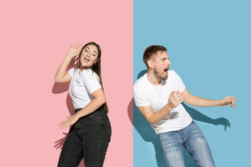 Celebrities. Dancing, moving, having fun. Young, happy man and woman in casual clothes on pink, blue bicolored background. Concept of human emotions, facial expession, relations, ad. Beautiful couple.