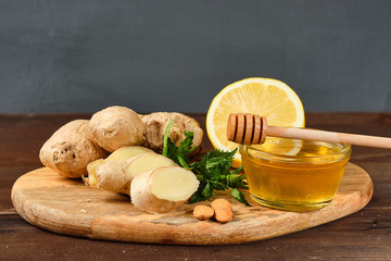 honey with ginger, lemon and mint and nuts on wooden Board and grey background.