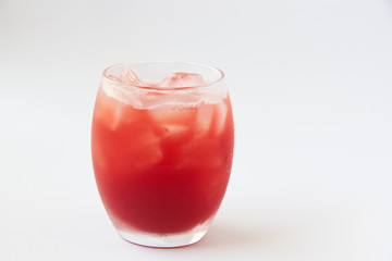 A glass of tasty cold strawberry juice with ice on the table.