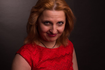 portrait of large blonde model in a red dress on a dark background in the Studio