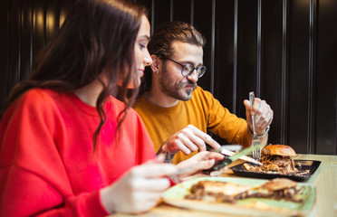 Young couple enjoying the tasty fast food in restaurant