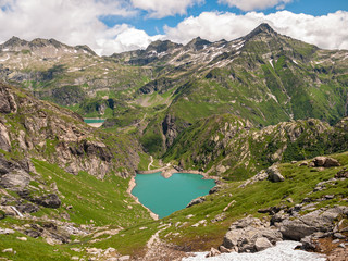 Stunning aerial panorama view of reservoir lake Lago del Zott, Lago di Robiei, Swiss Alps mountains in Canton of Ticino on summer sunny day, with blue sky cloud,  on hiking path, Tessin, Switzerland