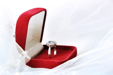 A red velvet box with an engagement, engagement ring in white gold and precious stones lies on a...