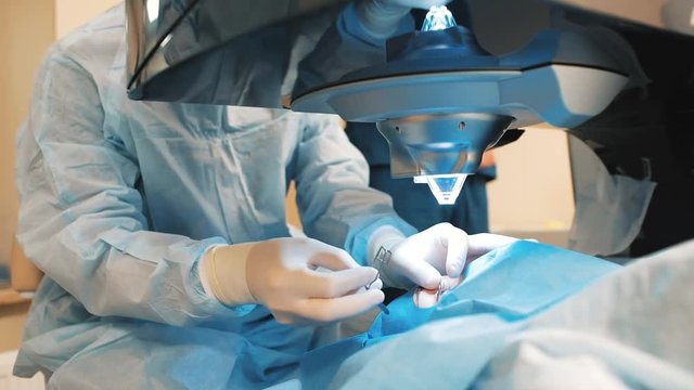 Laser vision correction. A patient and a surgeon in the operating room during ophthalmic surgery. Opened eye. Patient under sterile cover. Closeup
