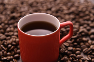 Red coffee cup with out of focus coffee beans in background