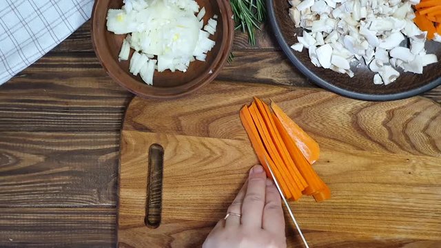Slicing ingredients for a rice dish with vegetables. Vegetarian dish. Mushrooms and carrots onions. Healthy diet. On a wooden background.