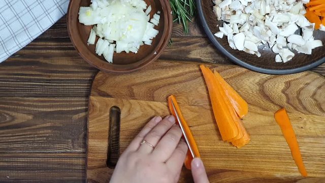 Slicing ingredients for a rice dish with vegetables. Vegetarian dish. Mushrooms and carrots onions. Healthy diet. On a wooden background.