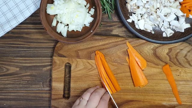 Slicing ingredients for a rice dish with vegetables. Vegetarian dish. Mushrooms and carrots onions. Healthy diet. On a wooden background.