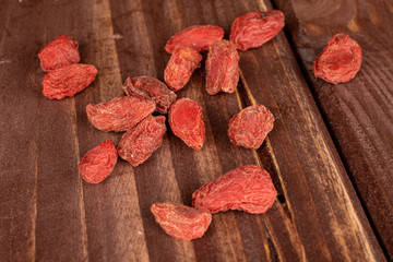 Lot of whole dried red goji on brown wood